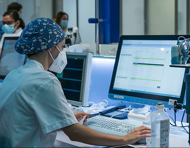 Healthcare worker sat at her computer looking at data Healthcare worker sat at her computer looking at data